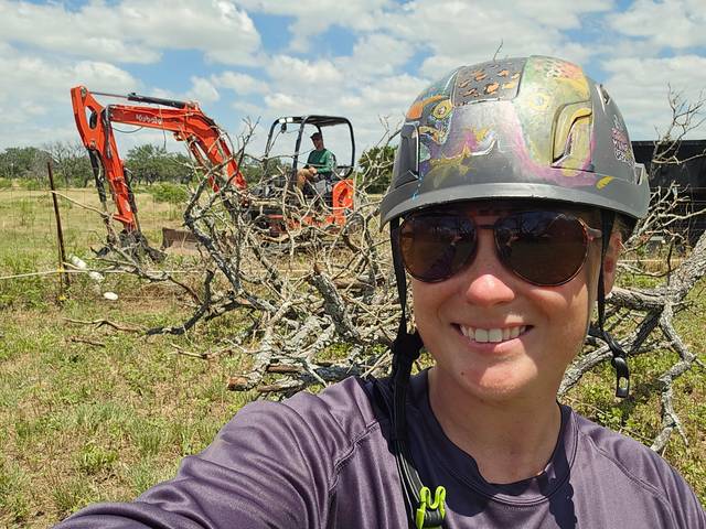 An excavator clearing scrub and brush from an open field