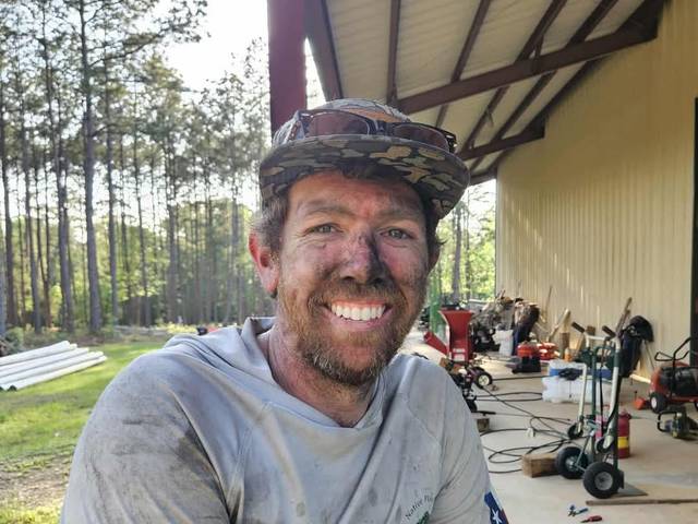 A crew member covered in sawdust and dirt, smiling at the end of a working day