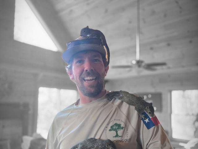 A crew member holding several young squirrels